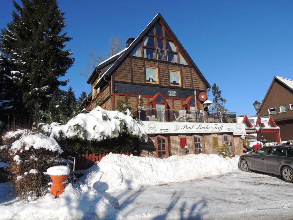 une maison recouverte de neige avec une voiture garée devant dans l'établissement Paul Lincke Residenz, à Hahnenklee