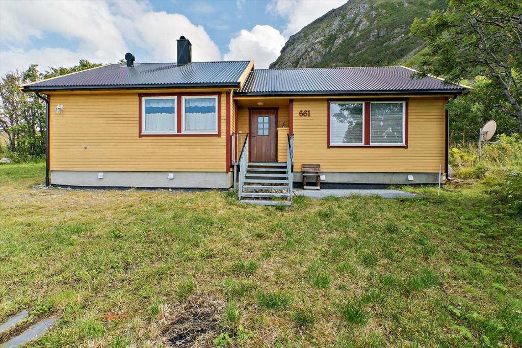 una casa amarilla con una escalera en un patio en Lofoten - Høynes, en Bøstad