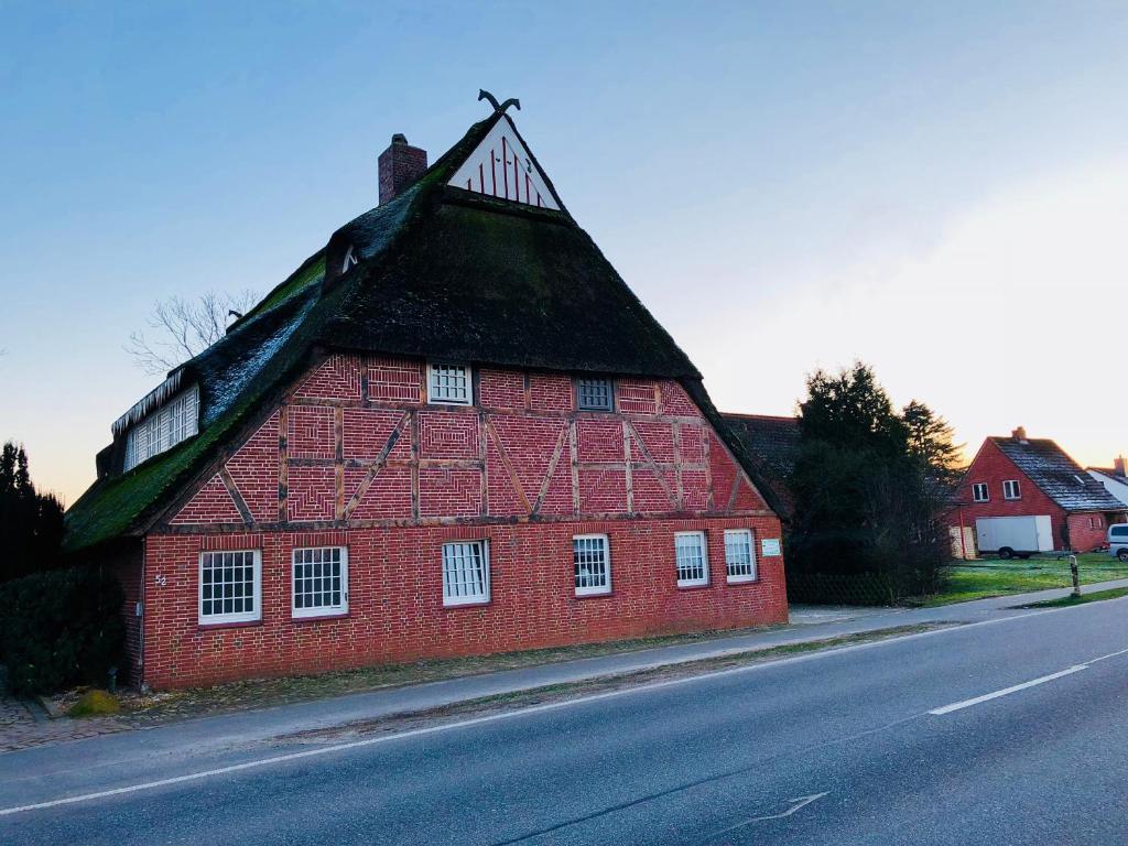 eine rote Scheune mit einem Dach an der Straßenseite in der Unterkunft Ferienwohnung Feldblick in Grevenkop