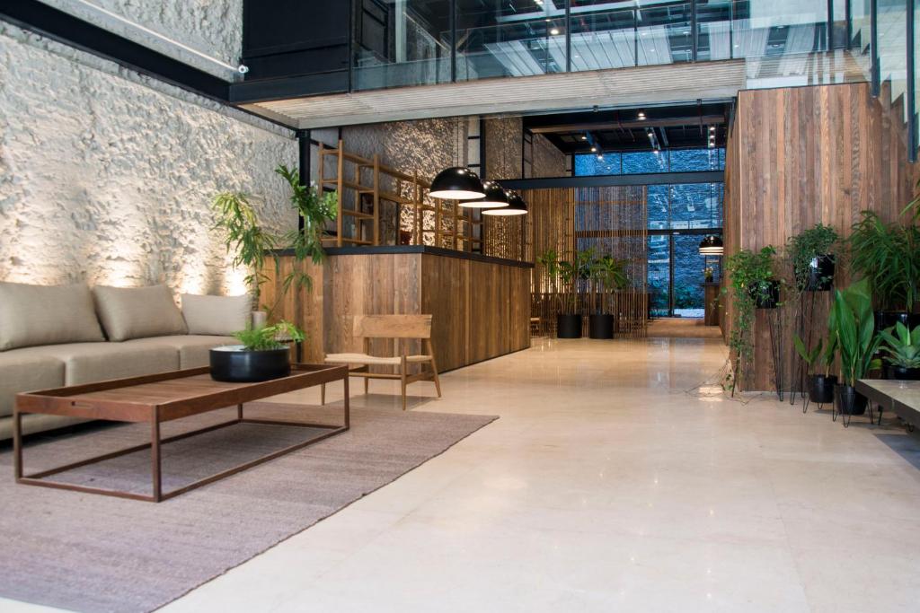 a lobby with a couch and tables and plants at AQ Tailored Suites in Buenos Aires