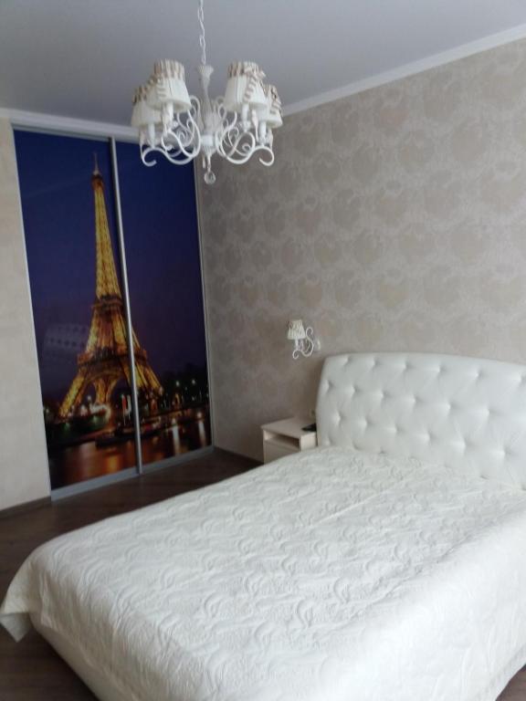 um quarto com uma cama branca e a torre Eiffel em Альтаир2 em Odessa