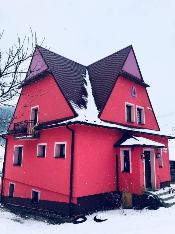 a large red house with snow on the roof at Malinowy Domek in Młyńczyska