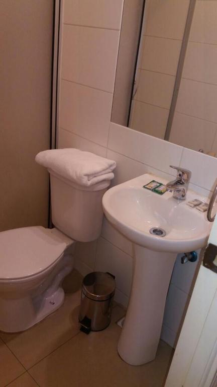 Un baño blanco con inodoro y lavabo. en Hotel Romano, en Concepción