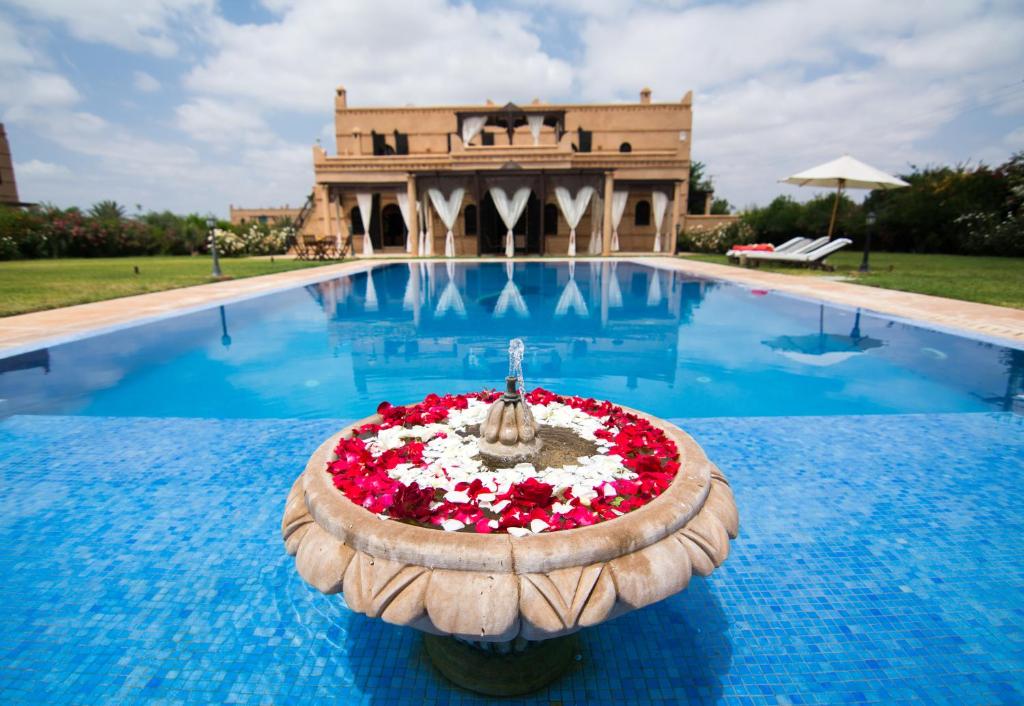 een zwembad met een fontein met rode en witte bloemen bij Villas Fleurs Marrakech in Marrakesh