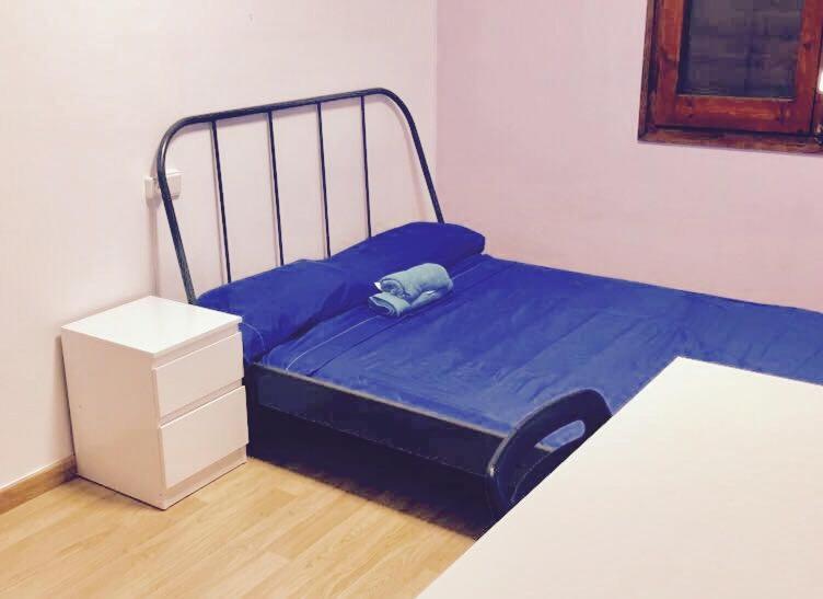 małe łóżko z niebieską pościelą w pokoju w obiekcie Apartamento Mataro w mieście Mataró