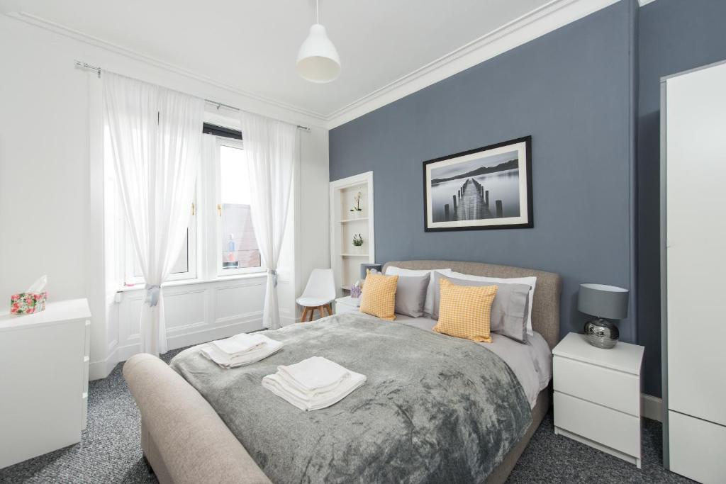 sypialnia z niebieskimi ścianami i łóżkiem z żółtymi poduszkami w obiekcie The Roseburn Apartment w Edynburgu