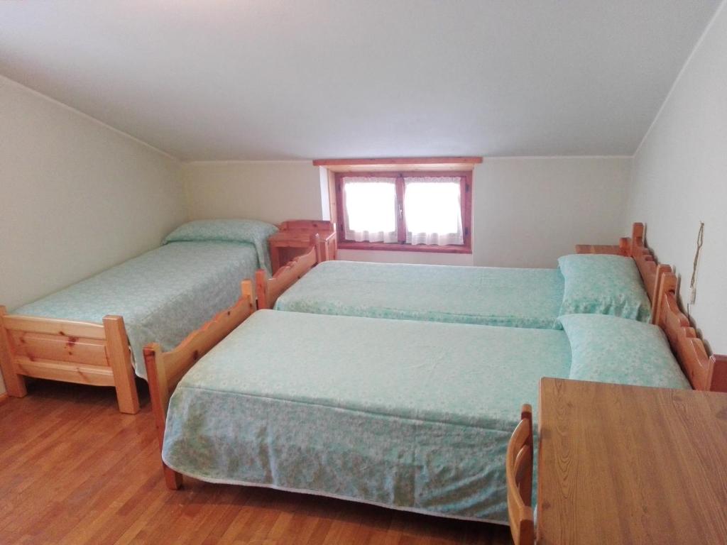een slaapkamer met 4 bedden en een tafel bij Chalet Bianco in Valdidentro