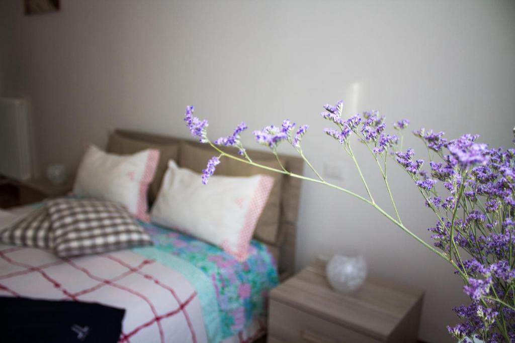 a bedroom with a bed and a bouquet of purple flowers at A due passi dal Lumière in Bologna