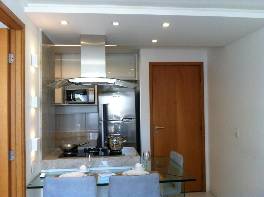 uma cozinha com uma mesa de vidro com cadeiras e um fogão em Flat 505, Edf. Home Club Porto Mar no Recife