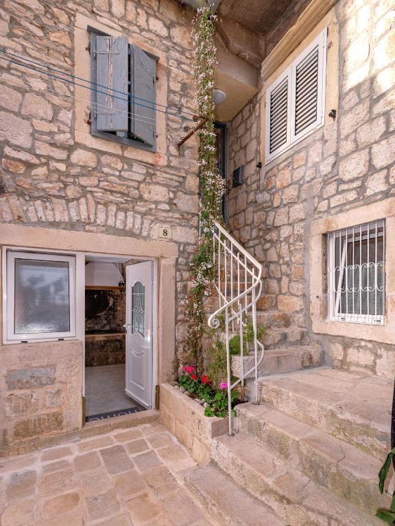 a stone house with a white door and stairs at Apartment Mediteran in Stari Grad