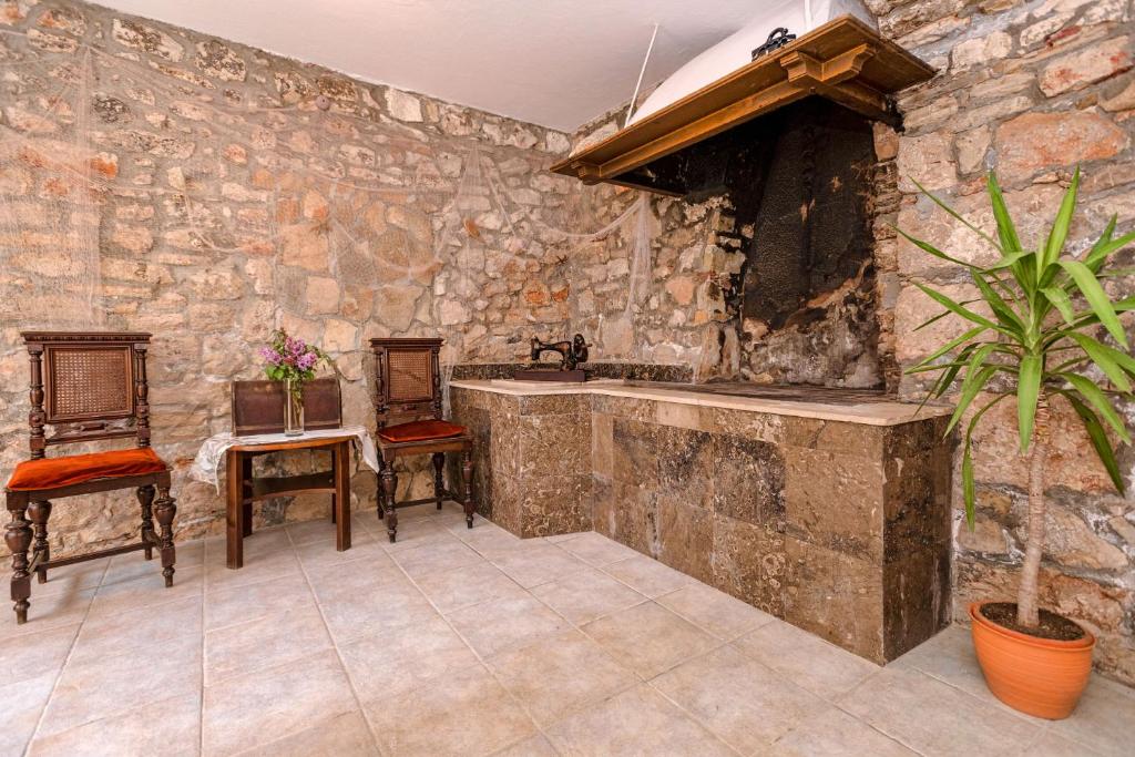 uma cozinha com paredes de pedra, um lavatório e cadeiras em Apartment Mediteran em Stari Grad