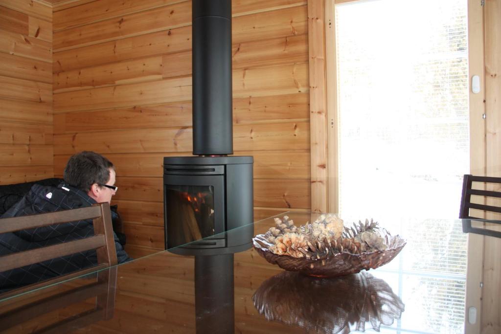 a man sitting in a room with a fireplace at Purolomat in Merikarvia