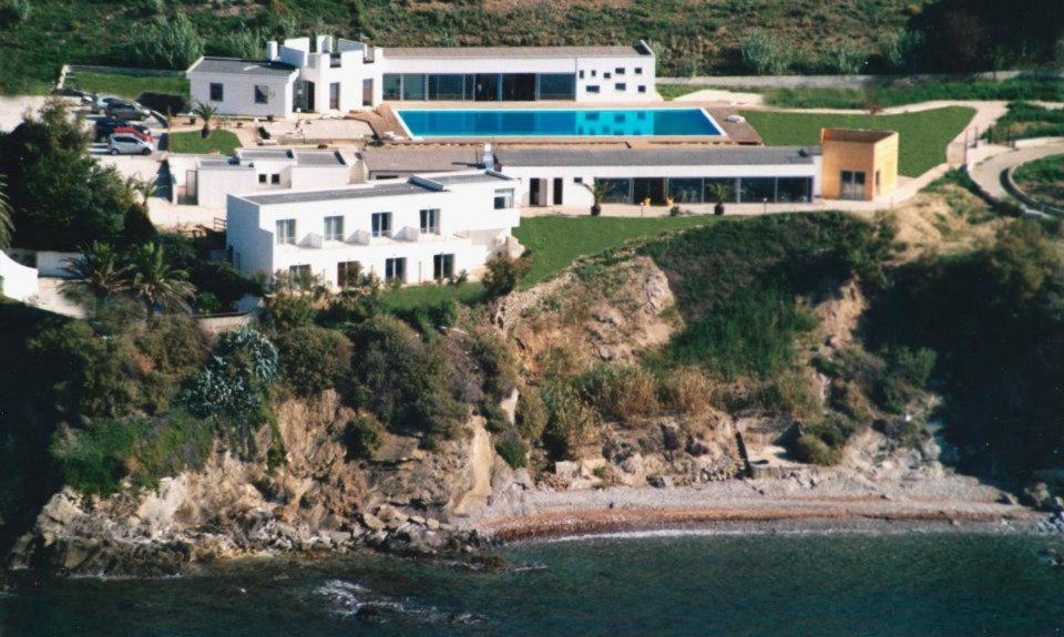 a house on a cliff next to the water at La Rosa dei Venti Resort in Piombino