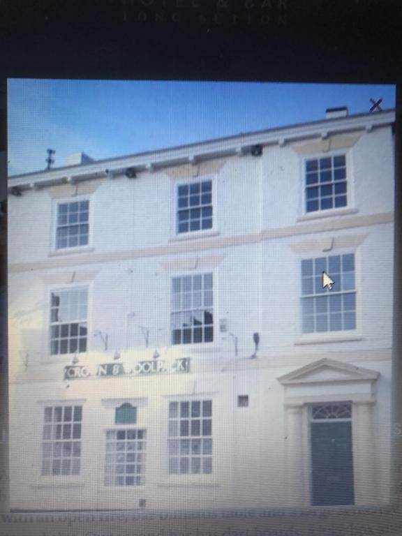 un edificio blanco con un cartel en el costado en The Crown and Woolpack en Long Sutton