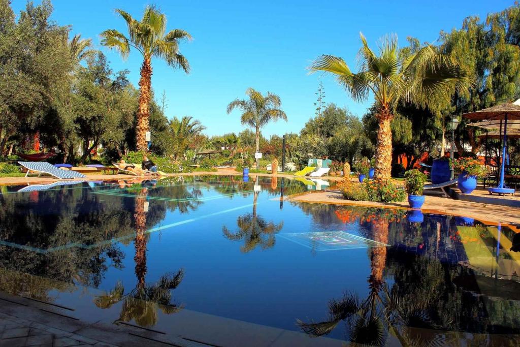 uma grande piscina com palmeiras num parque em Le Relais De Marrakech em Marrakech