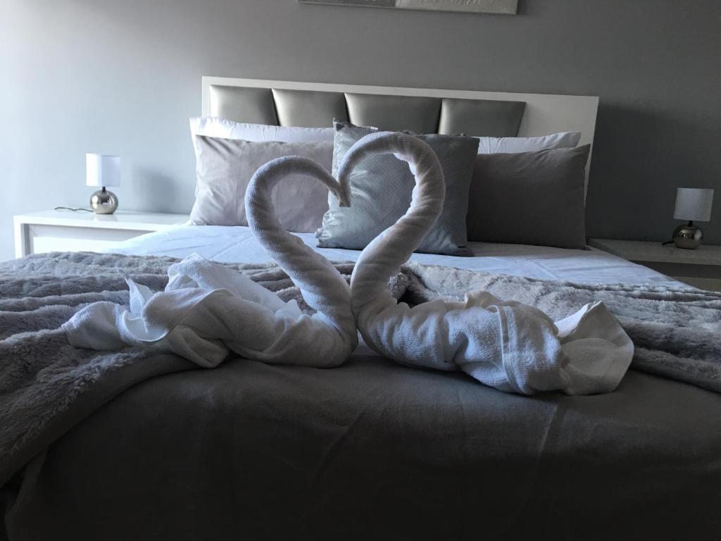 dois cisnes de toalha a fazer um coração numa cama em INVICTA HOUSE MARQUÊS no Porto