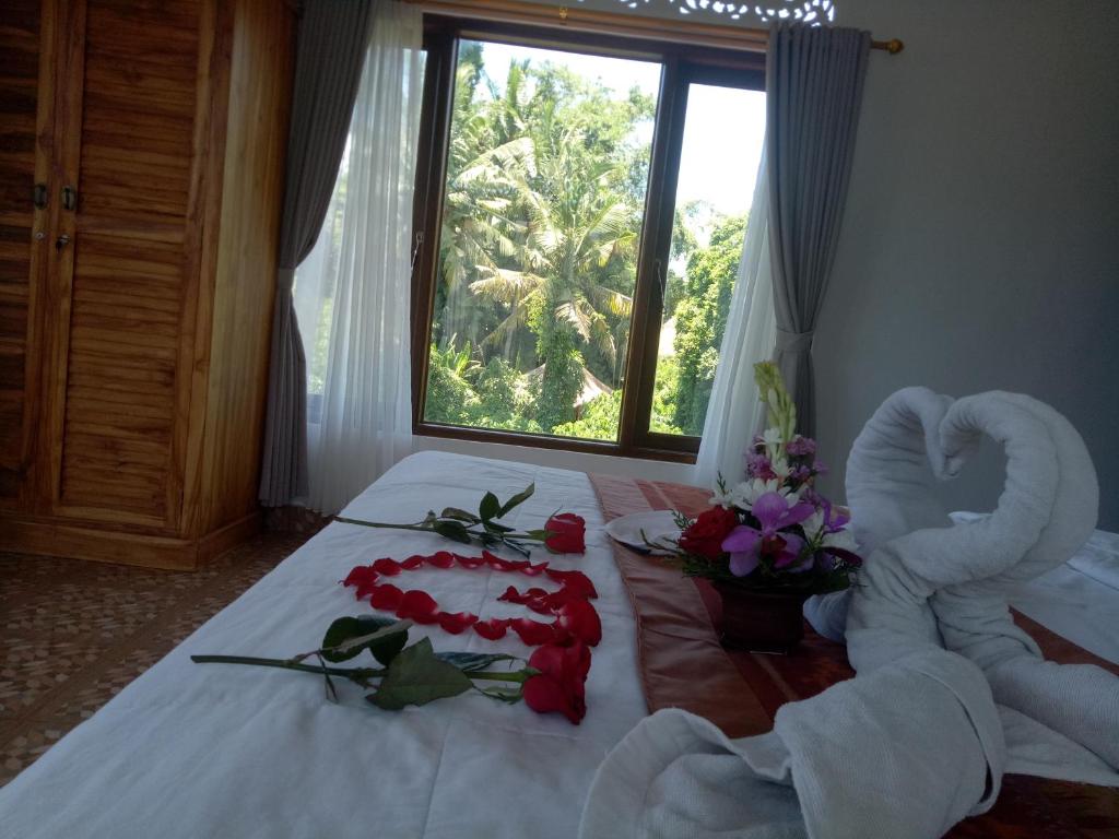 a room with a bed with a swan made out of roses at Karma House in Ubud