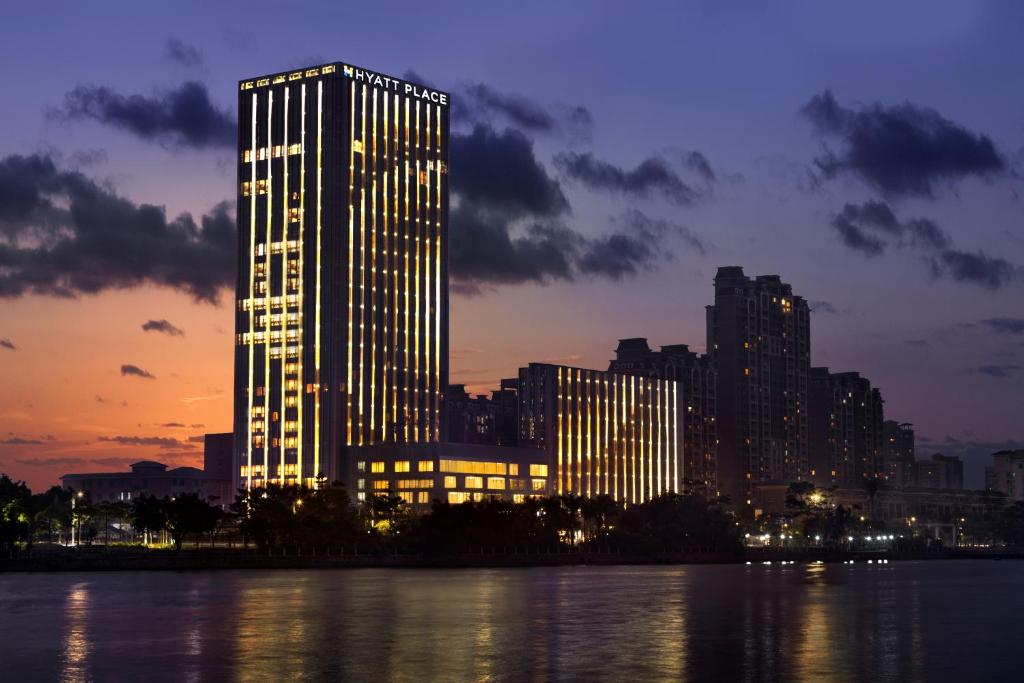 a tall building in front of a city at night at Hyatt Place Zhuhai Jinshi in Zhuhai