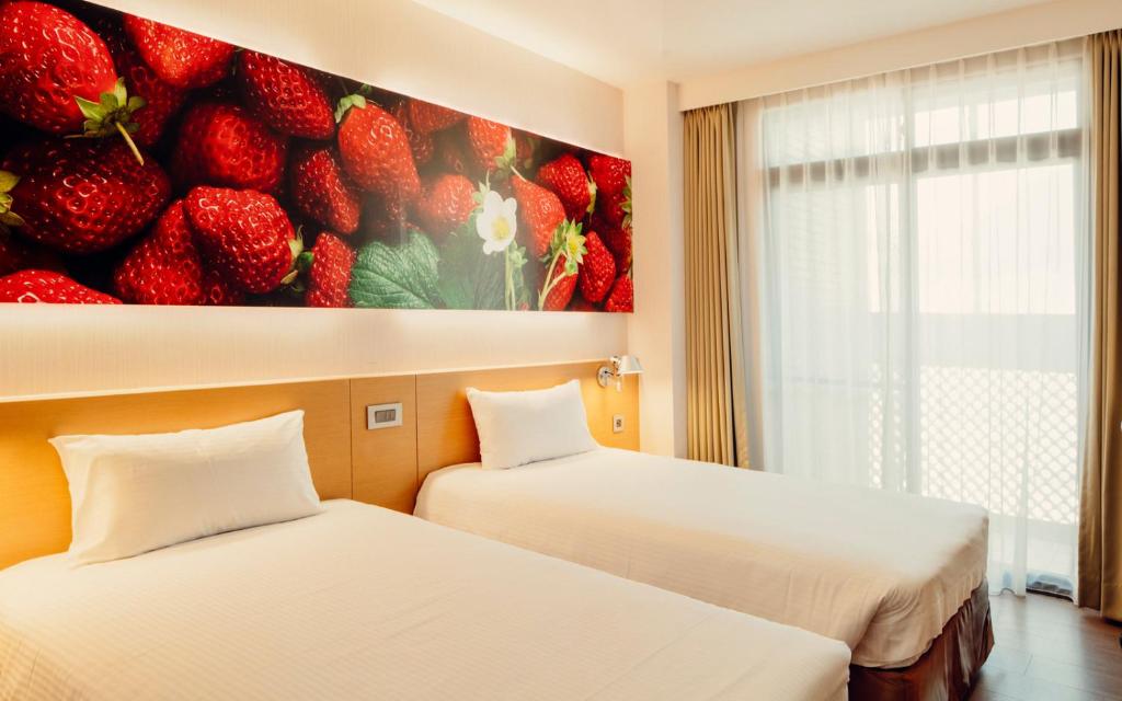 Mellow Fields Hotel في تايبيه: سريرين في غرفة مع لوحة بالفراولة