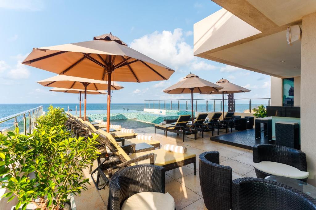 un patio al aire libre con mesas y sillas y el océano en Renuka City Hotel, en Colombo