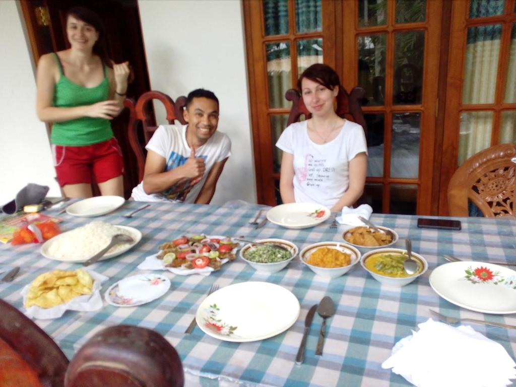 a group of people sitting around a table with food at Thuruliya Residence in Sigiriya