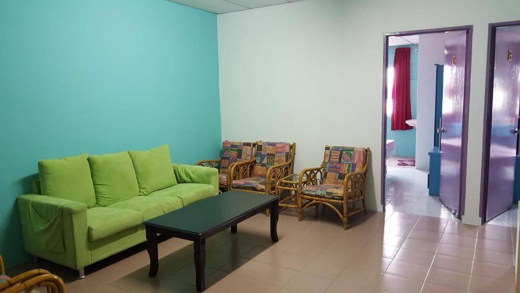sala de estar con sofá verde y sillas en Formosa Hotel Apartment, en Melaka
