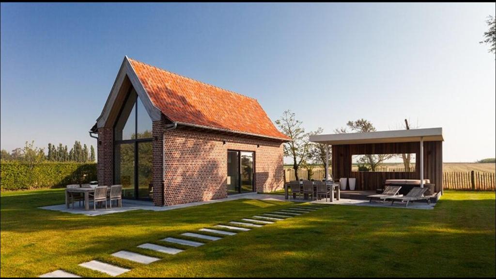a brick house with an orange roof on a lawn at Dream house in Poperinge