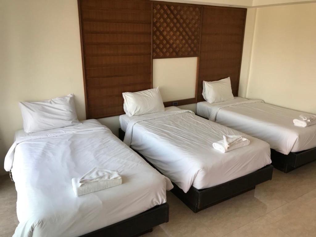 two beds in a hotel room with white sheets at David Residence in Nai Yang Beach