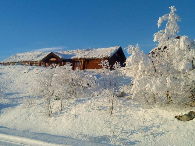 ein schneebedecktes Haus vor einem Haus in der Unterkunft Hakkesetstølen Hytter in Geilo