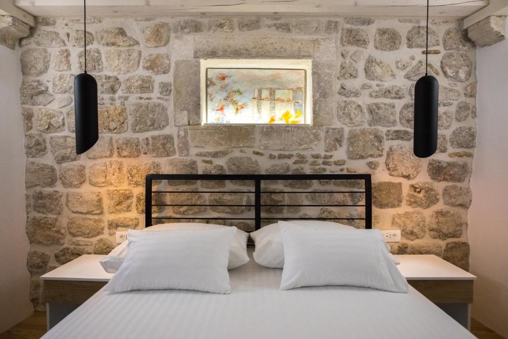 a bed in a room with a stone wall at Villa Four Winds III in Dubrovnik