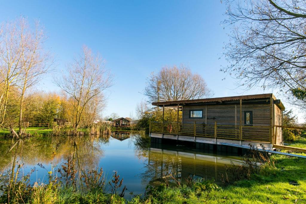 eine Hütte neben einem See in einem Park in der Unterkunft Fairwood Lakes Holiday Park in Westbury