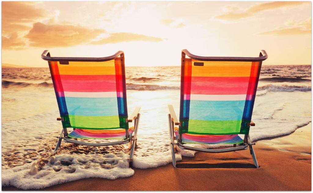 dos sillas sentadas en la playa cerca del océano en Willa Aura Mare en Władysławowo
