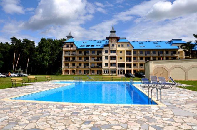 a large building with a swimming pool in front of it at Amber Blue Mare in Łukęcin