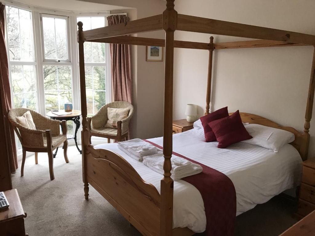 een slaapkamer met een bed met een houten bedframe bij The Abbey Inn in Buckfastleigh