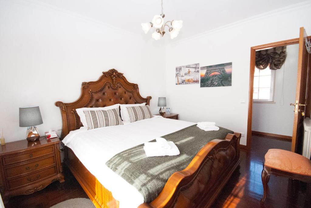 a bedroom with a large bed with a wooden headboard at Grace Villa in Aldeia de Juso