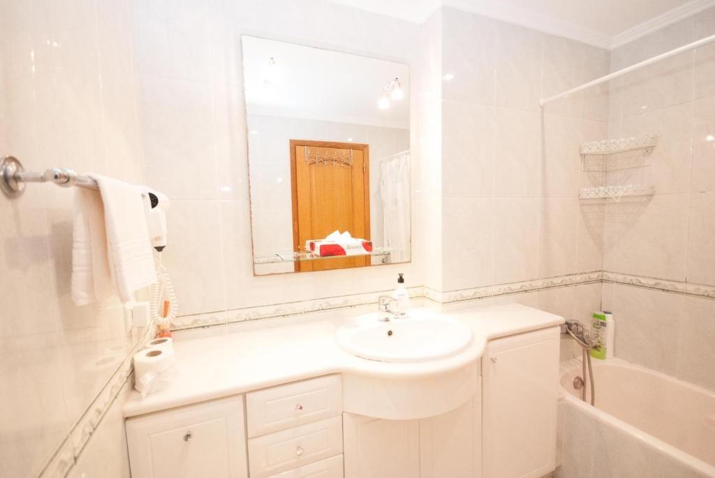 a white bathroom with a sink and a mirror at Grace Villa in Aldeia de Juso