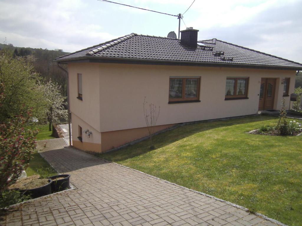 a small white house with a grass yard at Ferienwohnung Barzen in Ralingen