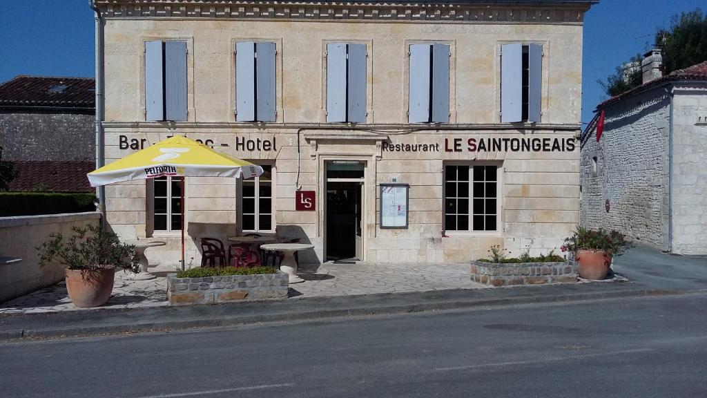 a building with a table and an umbrella in front of it at Le Saintongeais in Berneuil