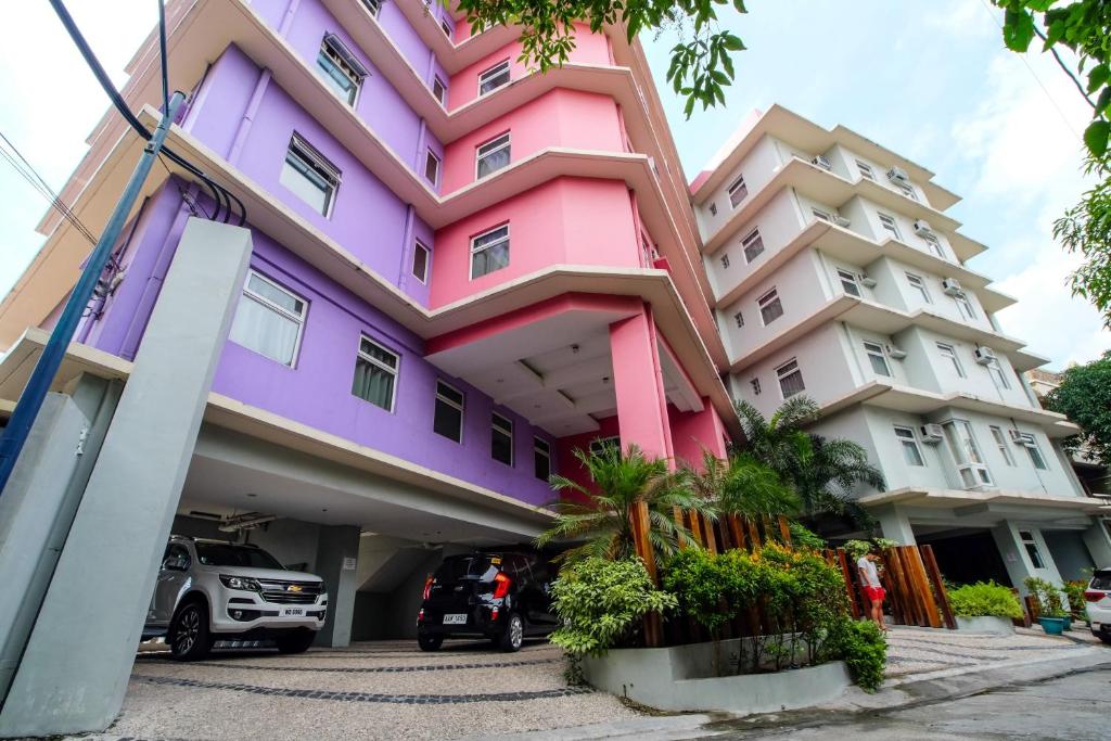 un bâtiment rose et violet avec un parking dans l'établissement MySpace Hotel @BGC, à Manille