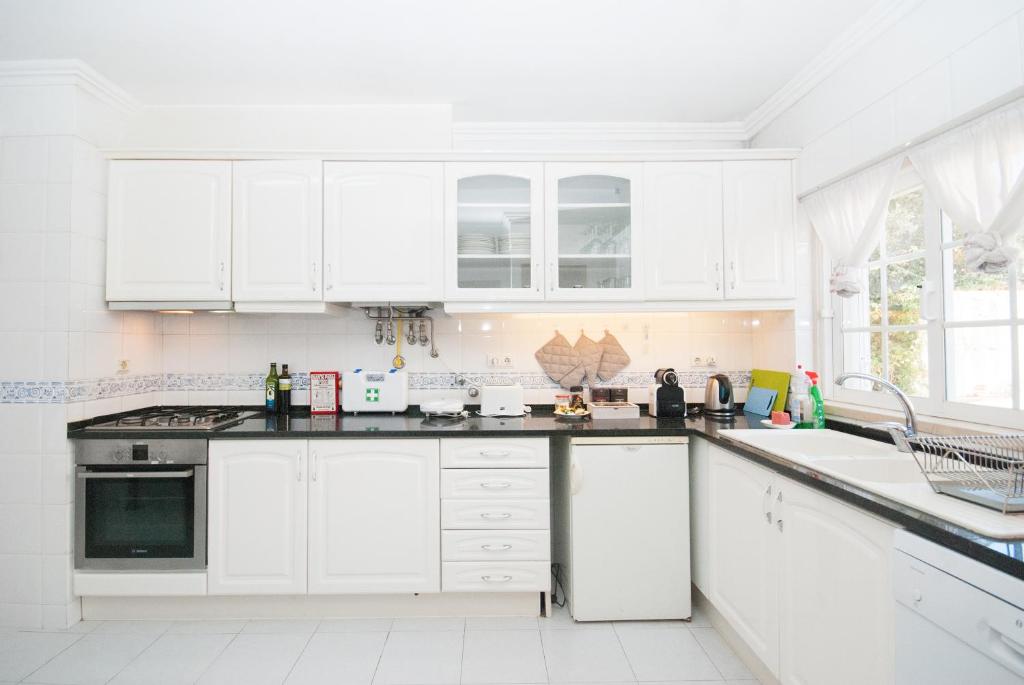 a white kitchen with white cabinets and appliances at Grace Villa in Aldeia de Juso