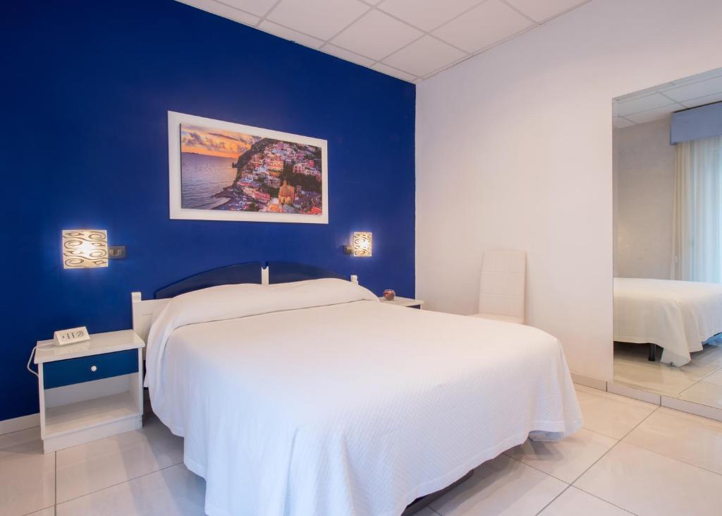 1 dormitorio con cama blanca y pared azul en House Matilde, en Sorrento