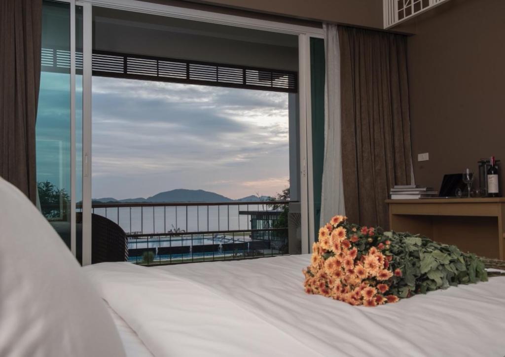 a bedroom with a bed and a large window at Baan Rim Ao in Chanthaburi