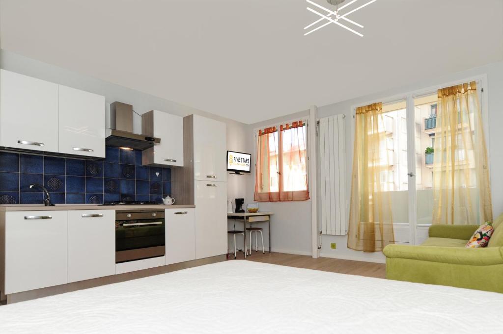 une cuisine avec des placards blancs et un canapé vert dans l'établissement Blue Lagon Five Stars Holiday House, à Nice