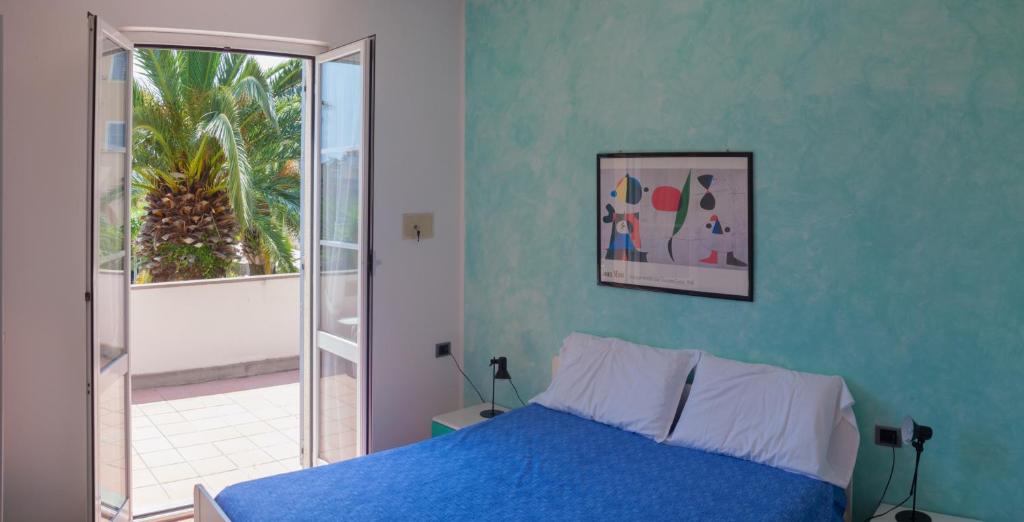 - une chambre bleue avec un lit et une fenêtre dans l'établissement Residence Pian Dei Boschi, à Pietra Ligure