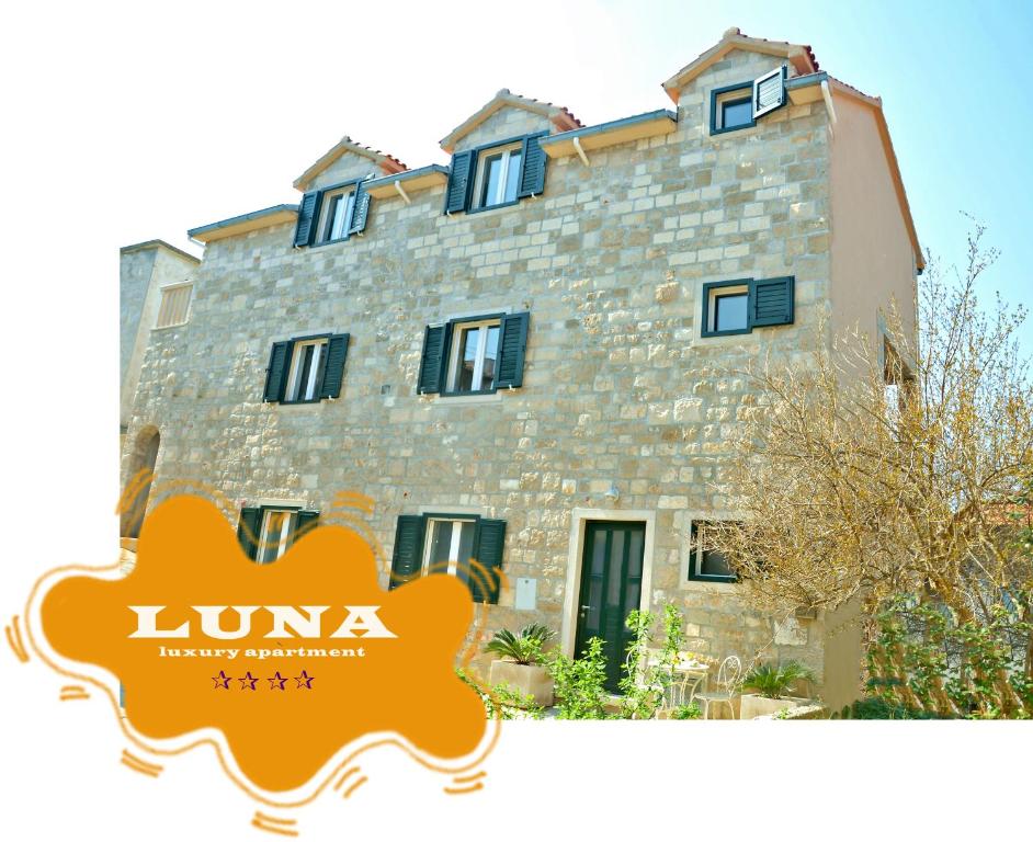 a large stone building with a sign in front of it at Apartment Luna in Postira