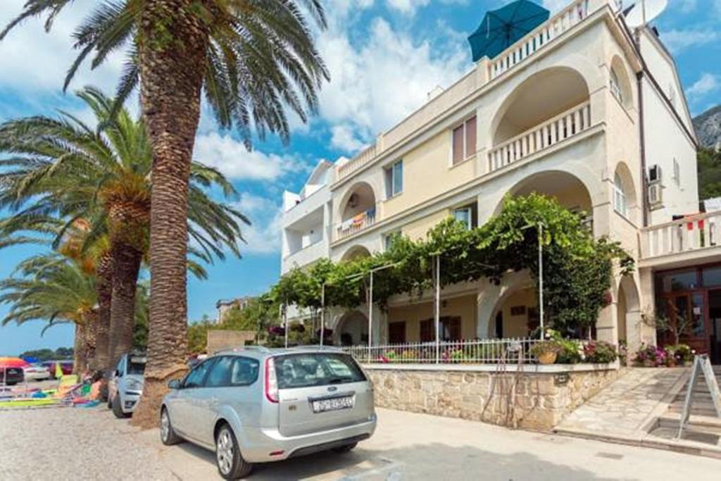 a car parked in front of a building with a palm tree at Apartments Pansion Franka in Brist