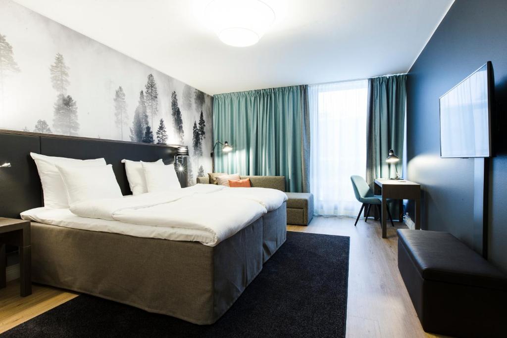 a hotel room with a large bed and a desk at Hotel Sveitsi in Hyvinkää