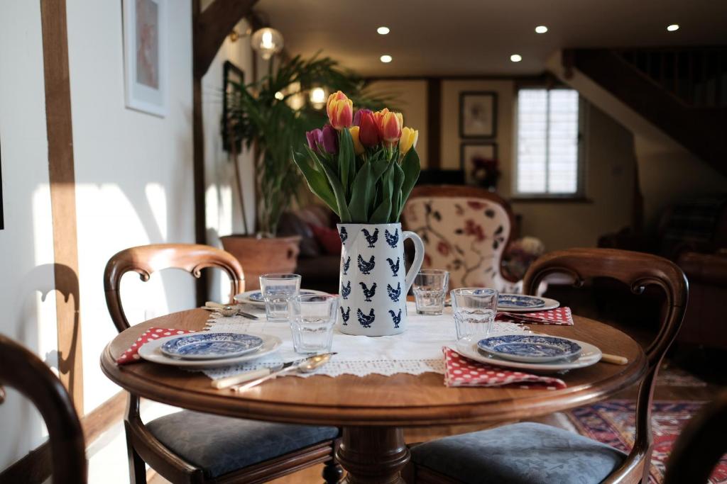 einen Holztisch mit einer Blumenvase darauf in der Unterkunft Stable Cottage in Dorking