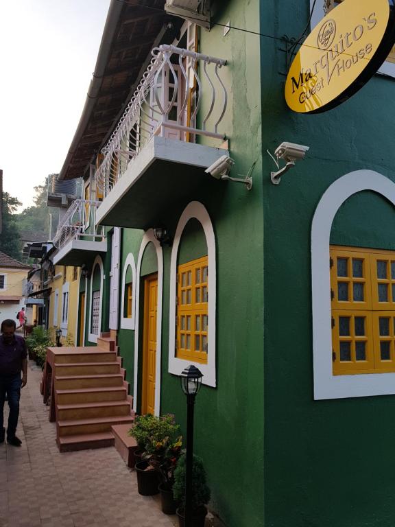 a green building with yellow doors and stairs on a street at Marquito's Guest House in Panaji