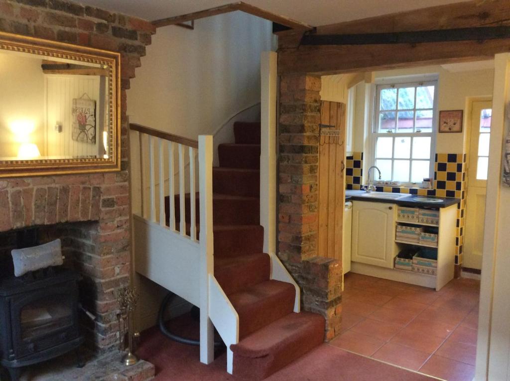 a living room with a staircase and a fireplace at Minty Cottage in Hythe
